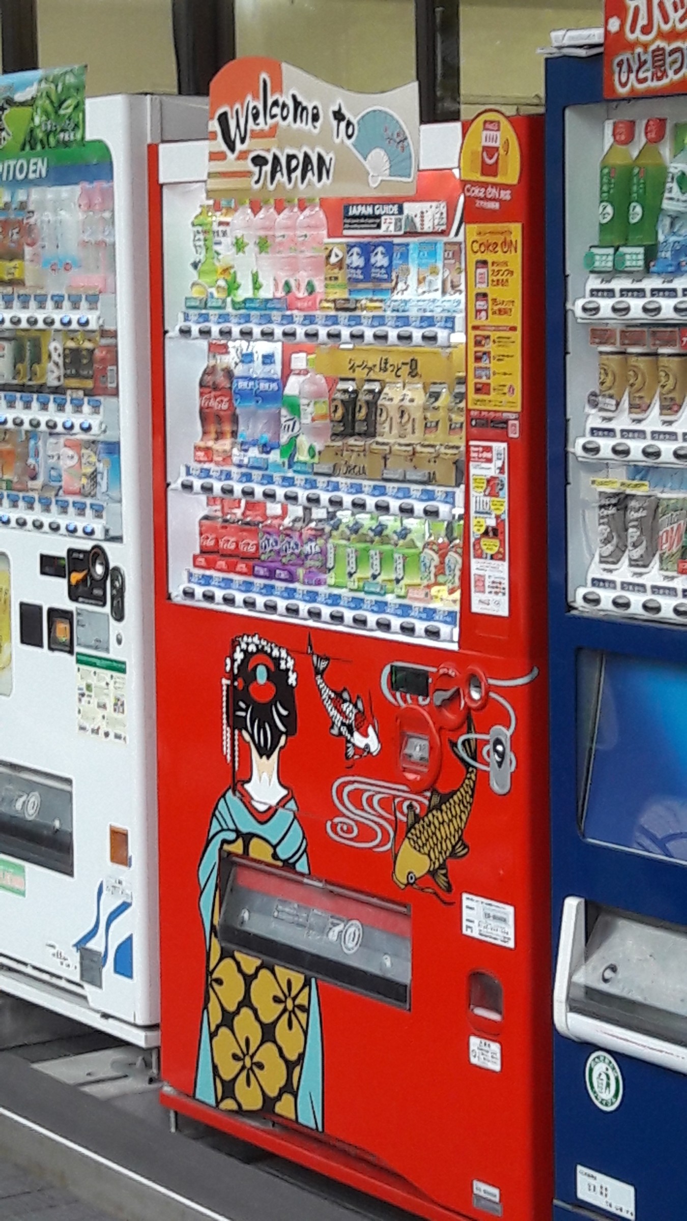 Distributore automatico rosso con la scritta Welcome to Japan, decorato con una geisha e due koi