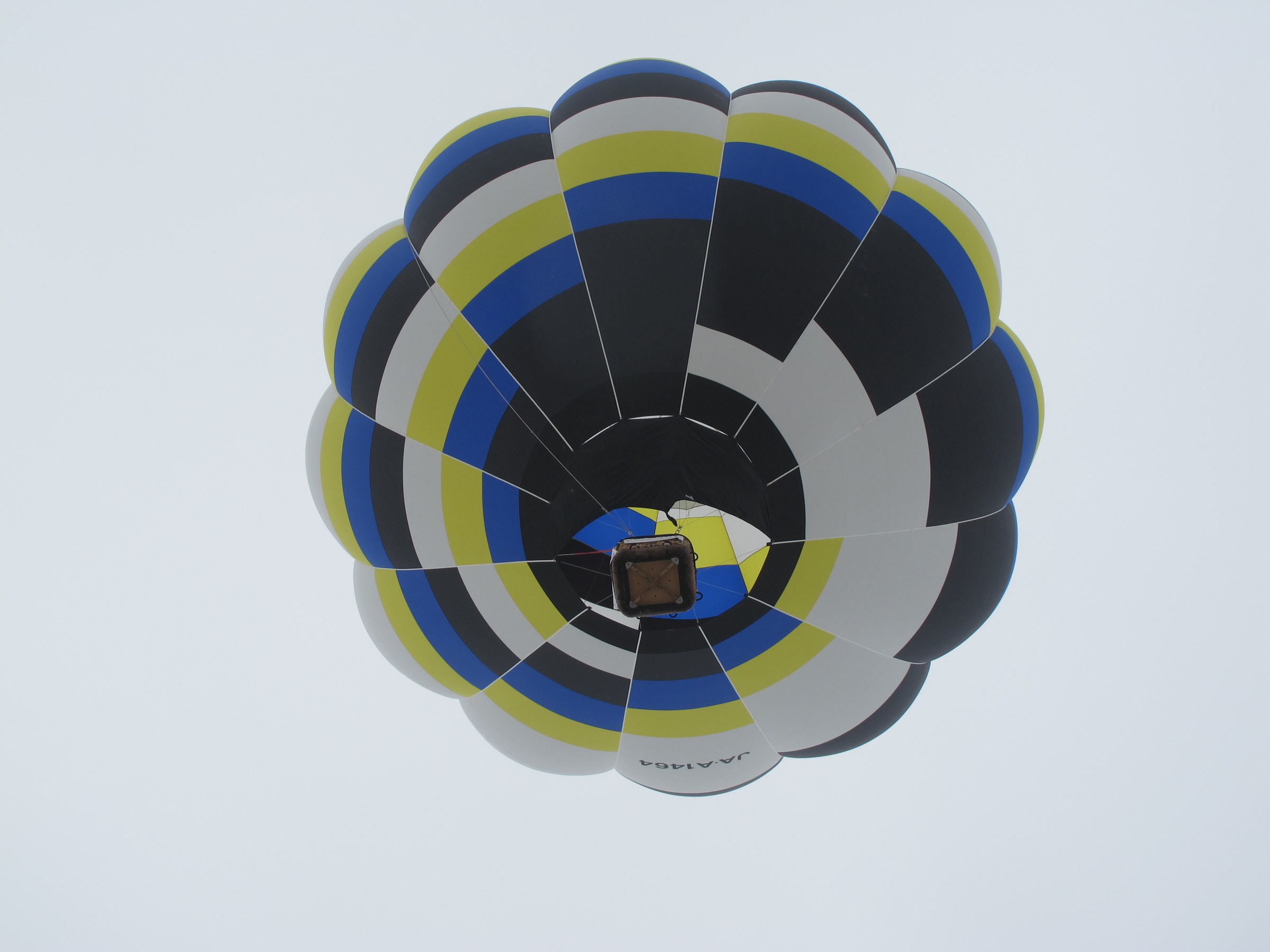 Mongolfiera blu e gialla vista dal basso, si vede il bruciatore