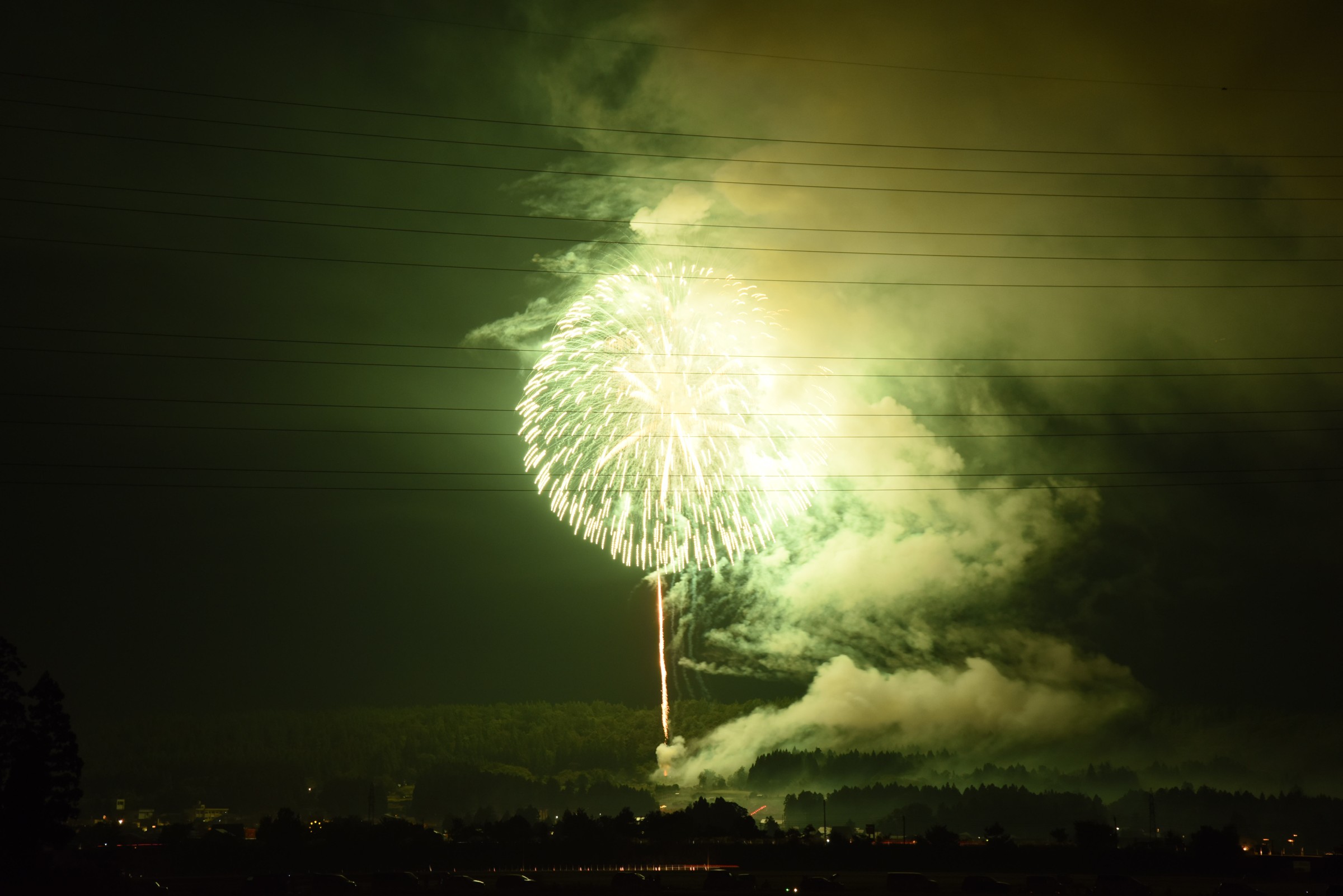 Fuochi d'artificio verdastri sopra la campagna buia