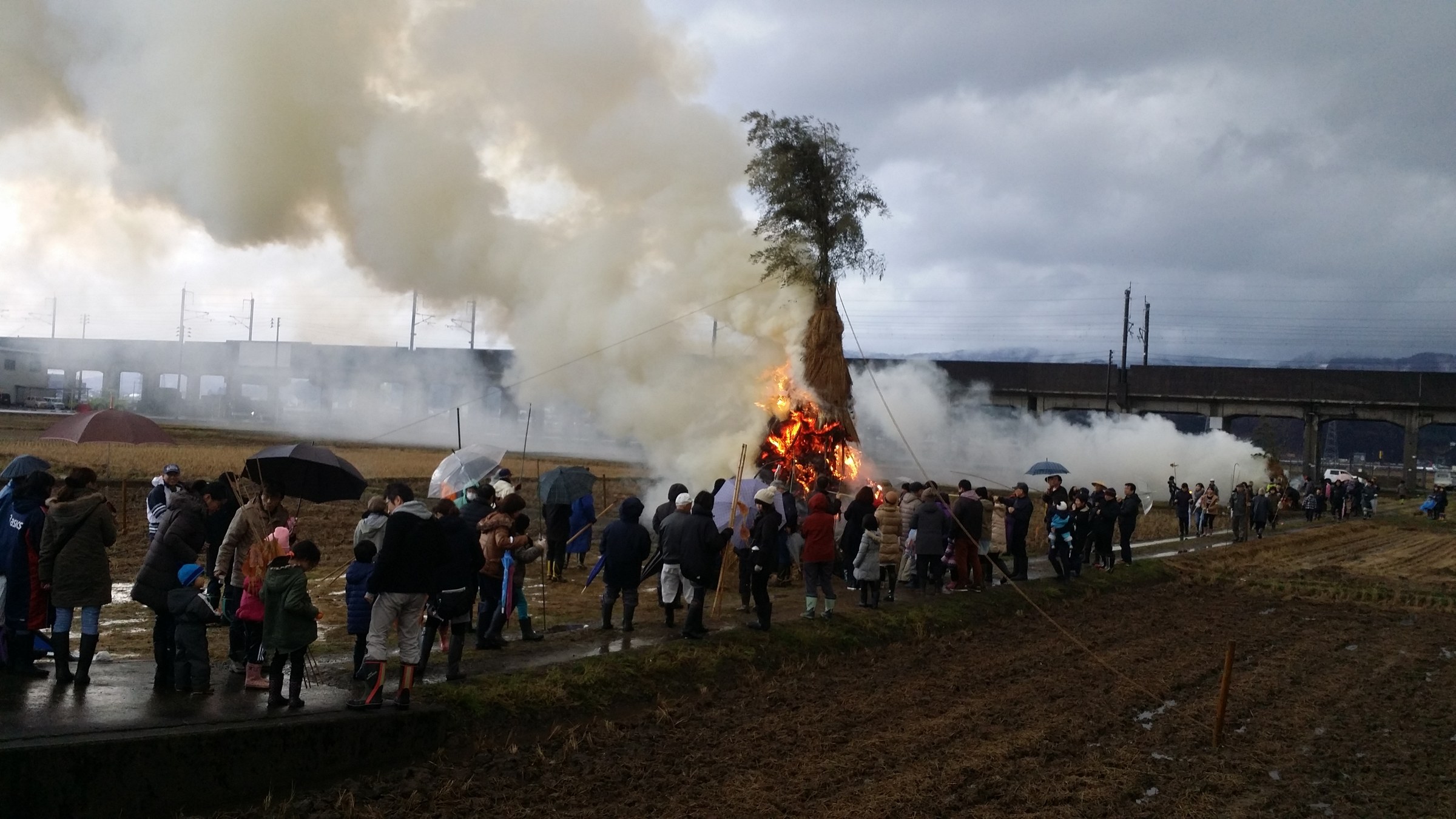 Cono di paglia in fiamme, davanti molti spettatori